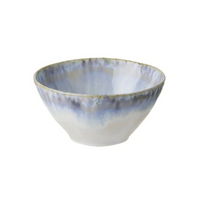 The Costa Nova Brisa Blue Dinnerware features smooth stoneware bowls with a wide opening and a watercolor glaze in blue, gray, and white, offering a slightly uneven, handcrafted look as part of the Brisa collection.