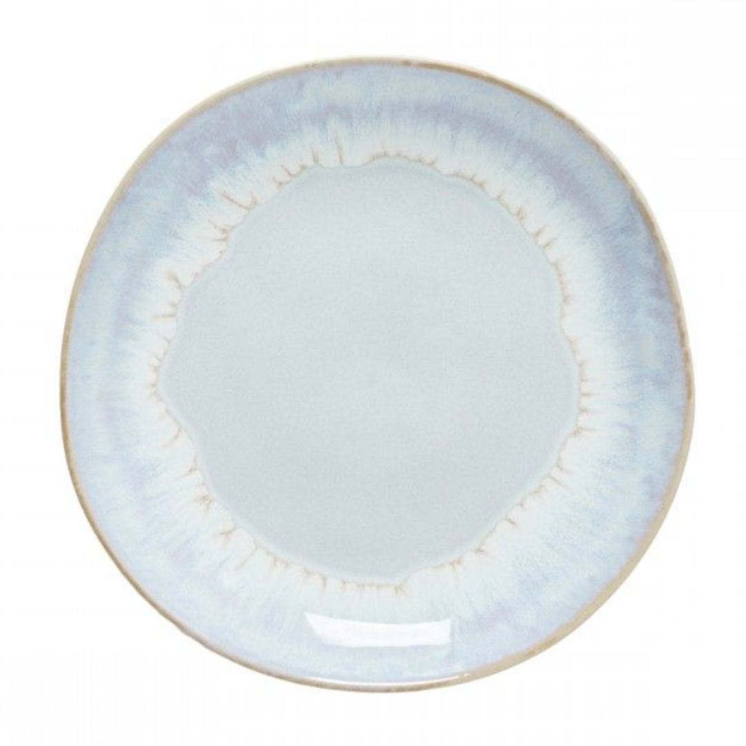 The Brisa Sal Dinnerware by Casafina/Costa Nova is a round, light blue stoneware plate with a subtle gradient pattern, slightly uneven rim, and glossy finish, inspired by the Algarve coast’s natural tones.