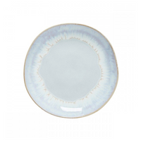 The Brisa Sal Dinnerware by Casafina/Costa Nova is a round ceramic plate inspired by the Algarve coast, featuring a white center, subtle uneven light blue glaze, thin beige rim, and a slightly irregular edge.