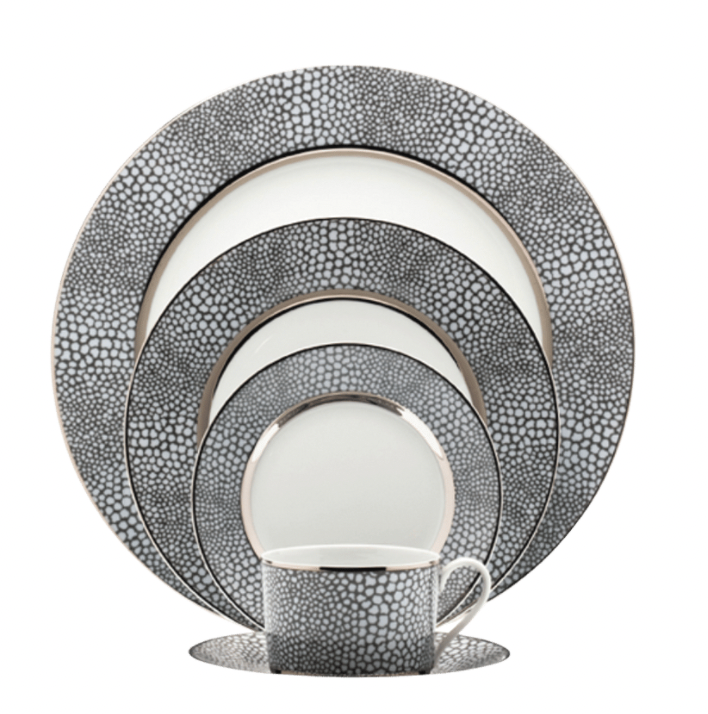 The Makassar Gray & Platinum Dinnerware set by Royal Limoges/Bia Cordon Bleu includes a handmade dinner plate, salad plate, bread plate, dessert plate, and cup with saucer in a black and white pebble design with metallic rims.