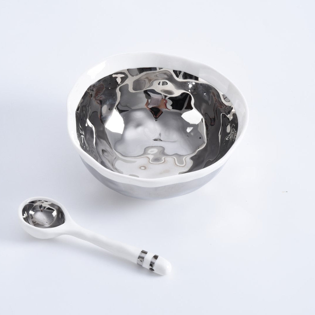 The Wavy Bowl & Spoon Set by PAMPA BAY features a metallic-silver porcelain bowl with a white exterior, paired with a matching spoon with a silver-finish interior and two silver bands on the handle, displayed on a white background.