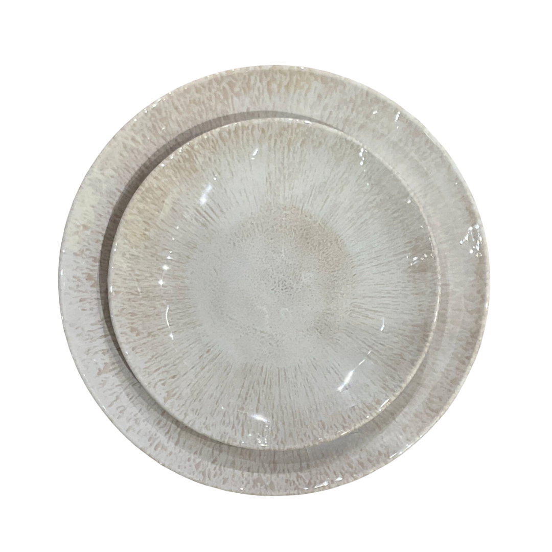 Two round beige Merritt Reactive Glaze Melamine dinnerware plates with a speckled pattern are stacked together, viewed from above on a white background, highlighting their refined stoneware-inspired style.