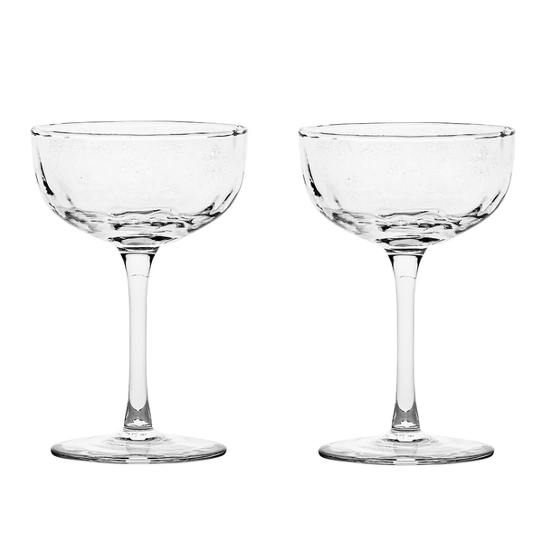 Two clear, empty Puro Cocktail Coupe glasses by Juliska, each featuring a short stem and wide, shallow bowl, are placed side by side on a plain white background—an ideal choice for serving elegant cocktails or gifting as a beautifully boxed set.