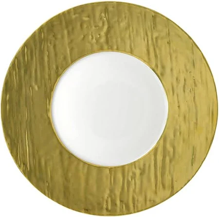 The Raynaud Makassar Metallic Charger features a smooth white center and a wide, textured metallic gold rim, blending elegance and modern design.