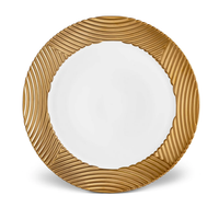 The L'Objet Corde Dinnerware Gold is a round white plate with a wavy, textured gold rim and a plain center—an elegant dinnerware piece that blends modern design with luxurious detail.