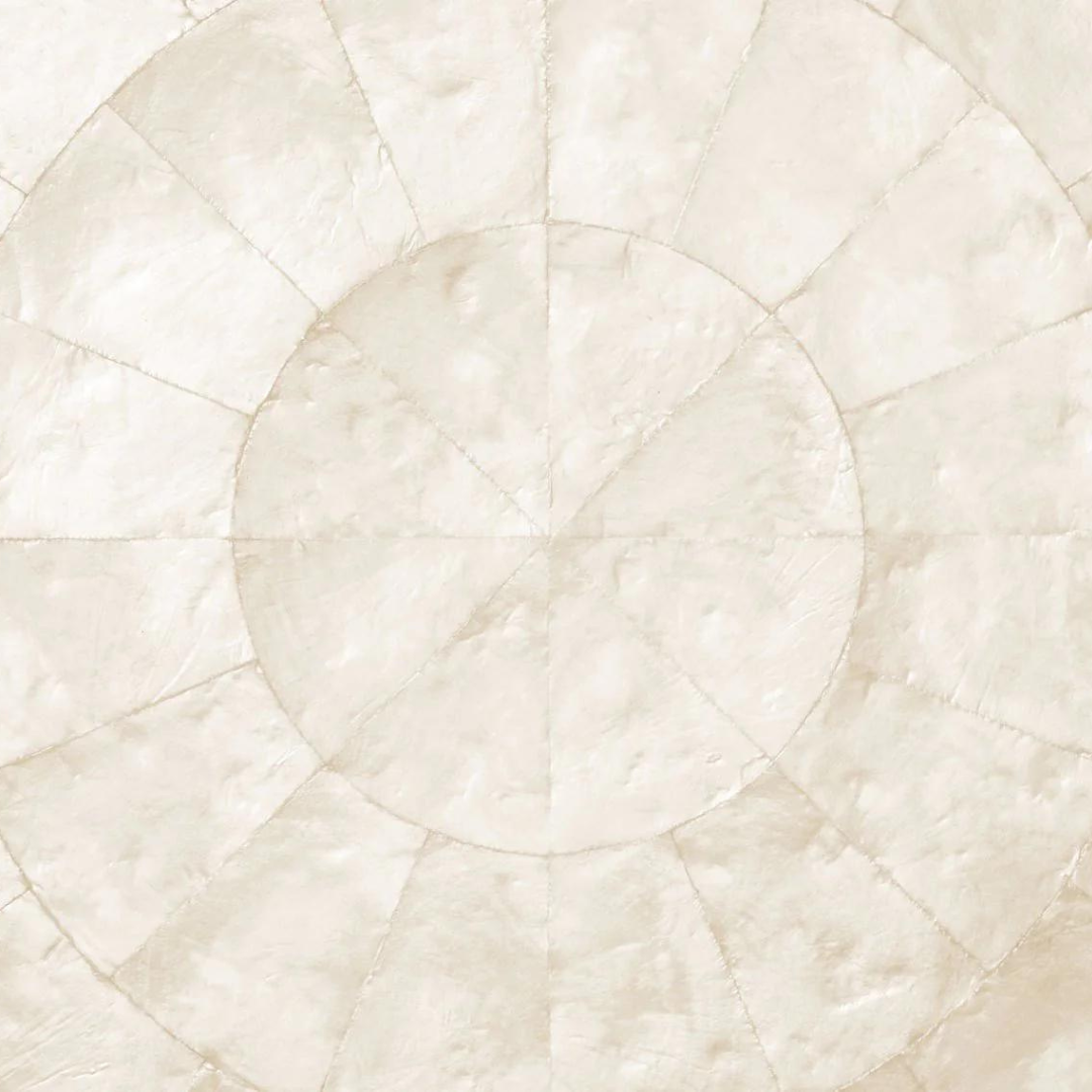 The Kim Seybert Capiz Shell Placemat Set of 4 in Natural features textured concentric circles and radial segments in off-white and cream, creating a geometric, artisanal look reminiscent of handcrafted placemats.