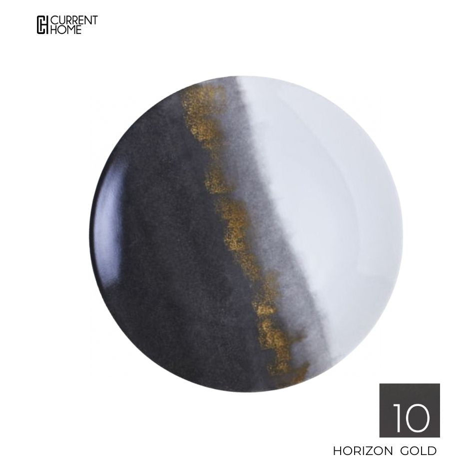 The Marie Daâge Horizon Gold Dinnerware features a round plate with a black-to-white gradient, a textured gold stripe center, and the brand name elegantly displayed on the bottom right.