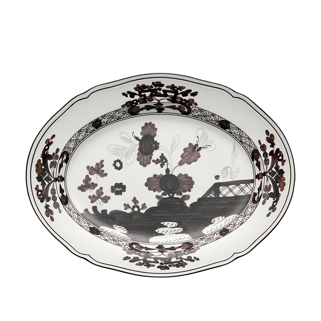 The Oriente Italiano Dinnerware Albus by Ginori 1735 is a handcrafted Italian white porcelain plate with scalloped edges, featuring intricate black and dark brown floral and geometric patterns on the rim and center.