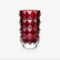The Baccarat Louxor Round Vase Red features a geometric diamond-cut pattern with a deep red interior and clear exterior, reminiscent of the iconic Louxor design, displayed against a plain white background.