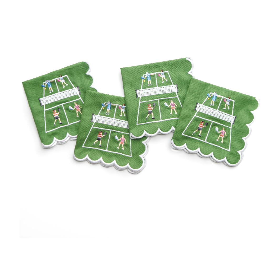 The Day At The Courts Cocktail Napkin Set of 4 by Pomegranate features green cotton napkins with white backgrounds and scalloped edges, each embroidered with a unique tennis scene.