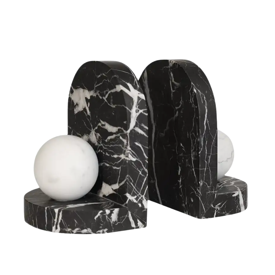 The Blitz Marble Bookend Set by Greg Natale features two black and white marble bookends with white veining and white marble spheres—an elegant new addition to luxury decor. Shown on a plain white background.