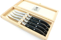A wooden box with a hinged lid holds four handcrafted Laguiole steak knives by Claude Dozorme. Each knife features a black handle and fits in its own groove, while the inside lid displays the Claude Dozorme brand label.