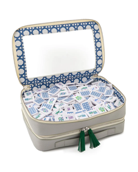 The Mahjong Debutante Travel Tile Set by Oh My Mahjong features a gray zippered case with green tassels, a large rectangular mirror in the lid, and blue patterned lining—perfect for travel or kids enjoying Mahjong on the go.