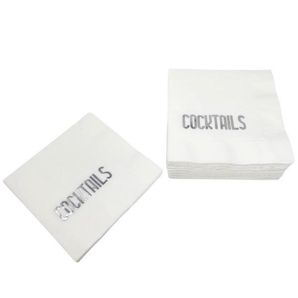 The Cocktail Napkin Pack - Cocktails White & Silver by Print Appeal is shown: a stack and a single white napkin, each featuring “COCKTAILS” in silver uppercase letters on a plain white background.