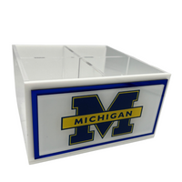 The Eye Candy College Spinner is a white plastic desk organizer box with multiple compartments, featuring the University of Michigan logo—a large blue M with "MICHIGAN" in yellow—on the front.