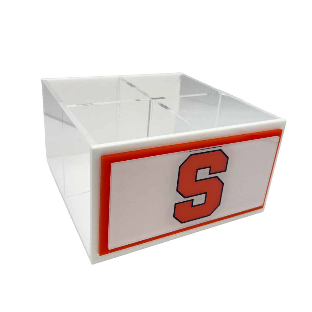 The Eye Candy College Spinner is a clear acrylic desk organizer with four compartments, a white front bordered in orange, and a bold orange S outlined in navy. Ideal for displaying your custom college logo.
