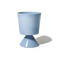 The Cariati Fiorelli Collection Vase - Dove features a modern, light blue design with a cylindrical top and cone-shaped base, inspired by handblown glass and shown against a white background with a faint shadow to the right.