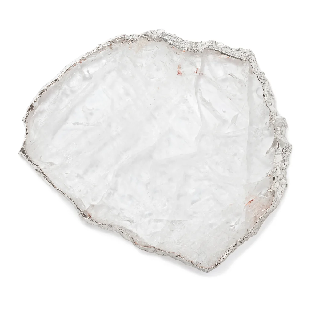 Introducing the Kiva Large Platter in Crystal/Silver by Anna New York—a thin, irregularly shaped translucent sheet with rough, wavy edges and a silvery border reminiscent of pure silver plating. Its frosted, glass-like appearance makes it the perfect striking addition to gemstone platters or an elegant challah board.