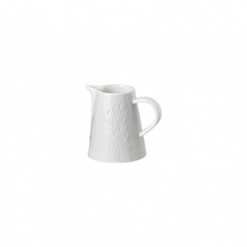 A small, white Raynaud Mineral Dinnerware Glazed White porcelain pitcher with a textured surface, curved handle, and narrow spout is set against a plain white background.