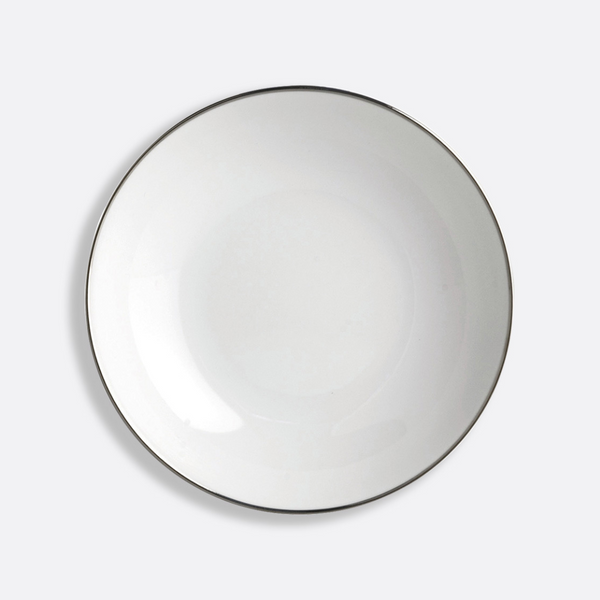 The Cristal Coupe Dinnerware by Bernardaud features a plain white ceramic plate with a thin platinum rim, photographed from above against a light gray background and inspired by Bernardaud’s renowned Limoges craftsmanship.
