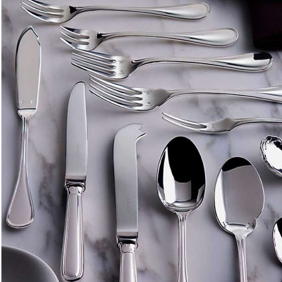 The Christofle Albi Flatware 5 Piece Setting - Silver Plated includes knives, forks, and spoons, elegantly displayed on a white marble surface.