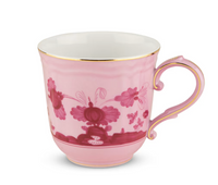 The Oriente Italiano Porpora teacup by Ginori 1735 features pink porcelain with a gold rim and handle, adorned with an intricate darker pink chinoiserie floral and butterfly pattern inspired by classic Ginori designs.