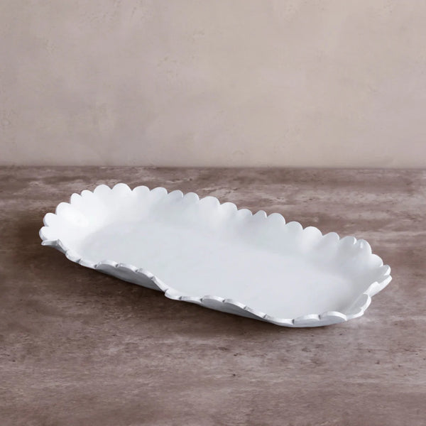 The Beatriz Ball Vida Colette Platter White - Large features a rectangular shape with scalloped, ruffled edges and sits on a brown textured surface against a beige wall—an elegant choice for outdoor entertaining.