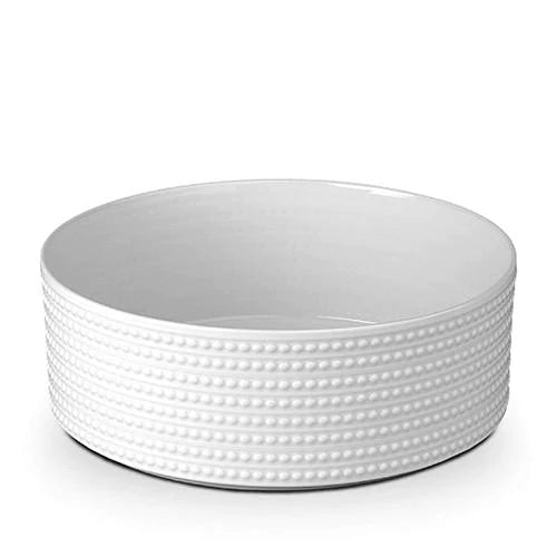 The Perlèe White Dinnerware bowl by L'Objet, crafted from Limoges porcelain, features a textured exterior with horizontal rows of raised dots and is shown on a white background.