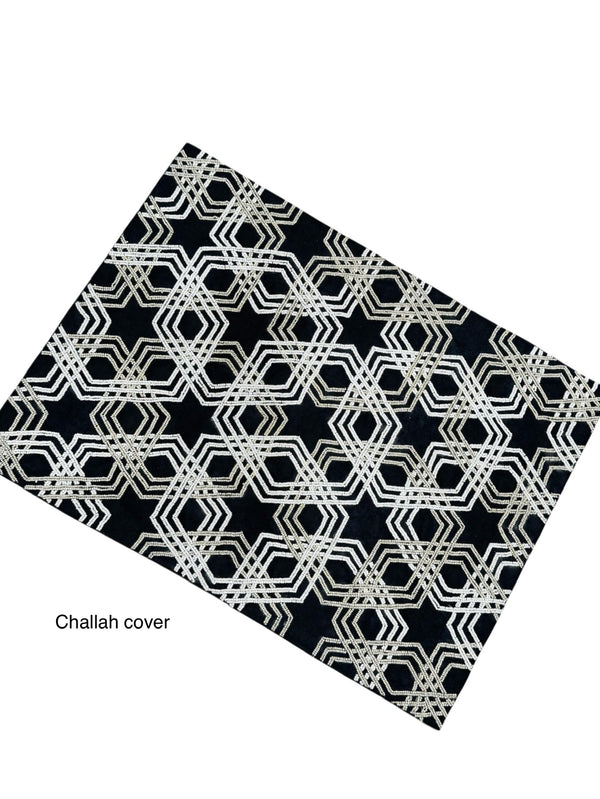 The Lyss & Kat Beaded Star of David Challah Cover features a black background with an intricate geometric white and gold pattern, subtle Star of David details, and "Challah cover" in small text at the lower left.