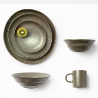 The Marcus Gray Salt Dinnerware Set of 4 by Blue Pheasant includes a plate, bowl, mug, and salad bowl in artisanal speckled ceramic. Microwave safe, it adds charm to any table; a sliced kiwi sits on the smallest plate in the photo.