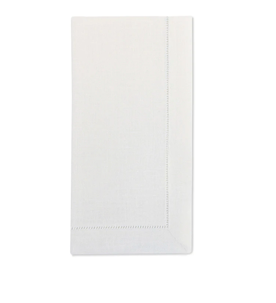 A set of four neatly folded, plain white Sferra Festival Napkins made from luxurious European linen, each featuring a subtle stitched border and displayed on a white background.