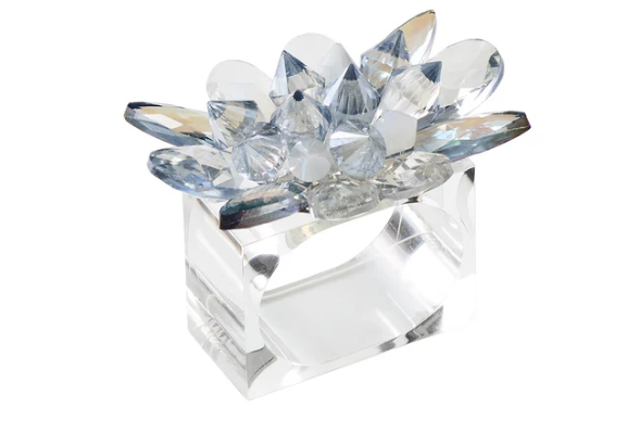 The Kim Seybert Spectra Napkin Ring Set of 4 in Glacier Blue features clear rectangular rings topped with faceted crystal shapes in a floral crown design, adding sparkling elegance to your table décor.