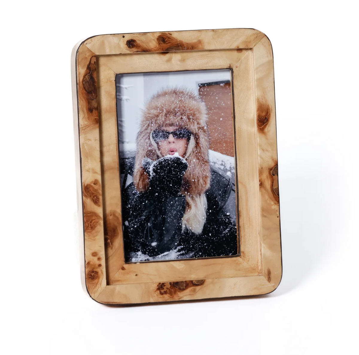 A woman in a fur hat and sunglasses blows snow in a photo displayed in the Zodax Valari Burl Veneer Frame.