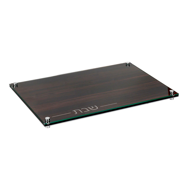 The BT-Shalom Lucite and Glass Wood Challah Board features a modern rectangular design with metallic corners, a dark wood-patterned base, and elegantly etched Hebrew text—perfect for Shabbat.