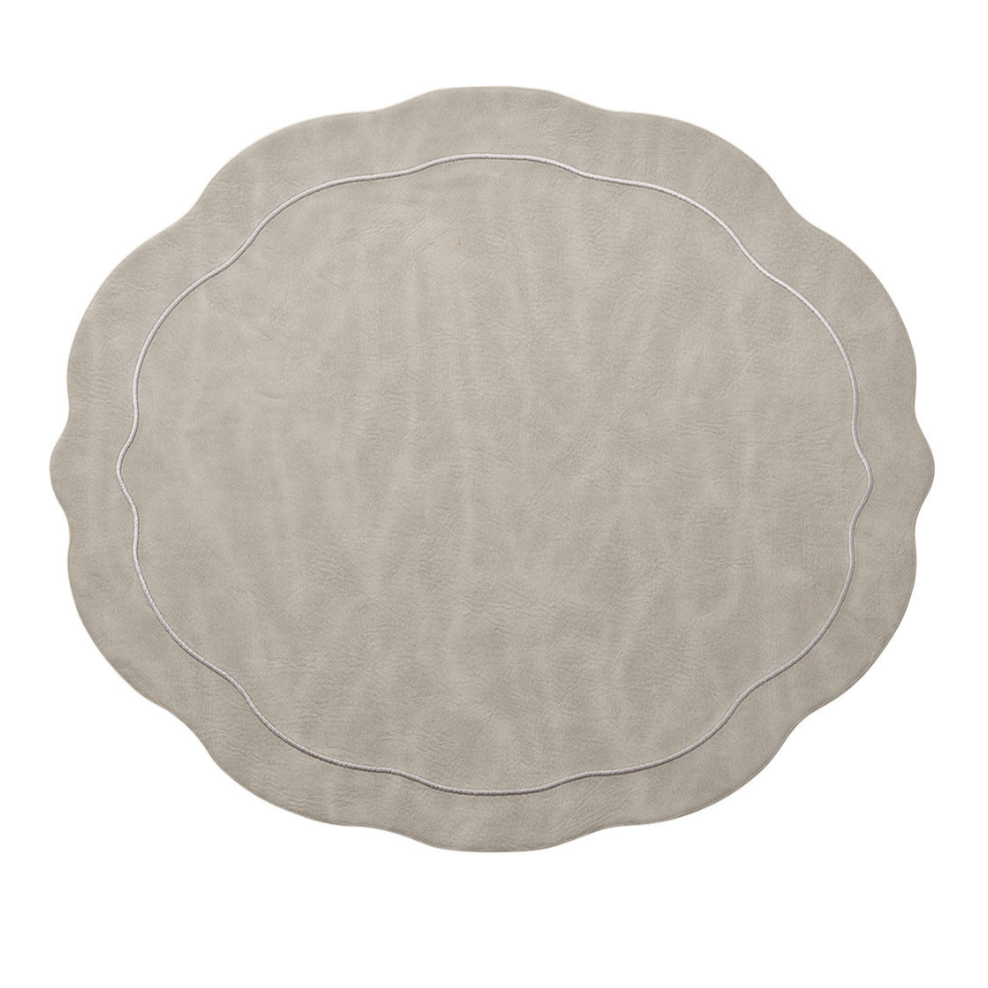 The Kim Seybert Tailored Placemat Gray Set of 4 features a matte faux leather finish, wavy edges with scalloped detailing, and a thin decorative rim line, shown here against a white background.