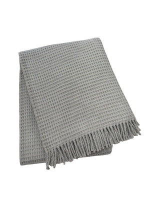 The A Soft Idea Basic Waffle Throw is a folded light gray cotton-acrylic blanket with a waffle pattern and fringed edges, shown on a white background.