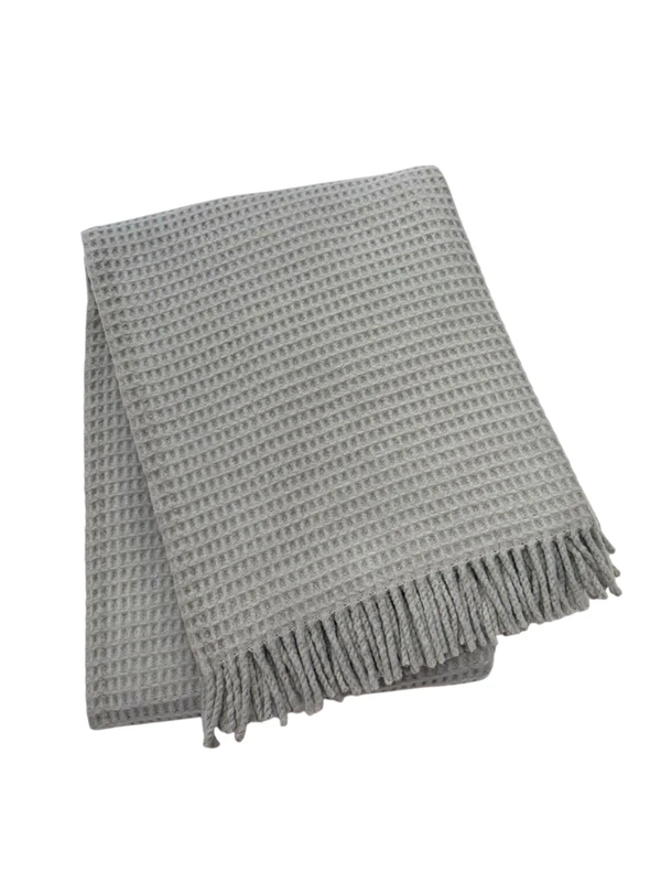 The A Soft Idea Basic Waffle Throw is a folded light gray cotton-acrylic blanket with a waffle pattern and fringed edges, shown on a white background.