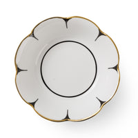 The Drops Dinnerware saucer by Molecot features white Limoges porcelain, scalloped flower-shaped edges, black accent lines radiating from each edge, and a gold-finished trim along the rim.