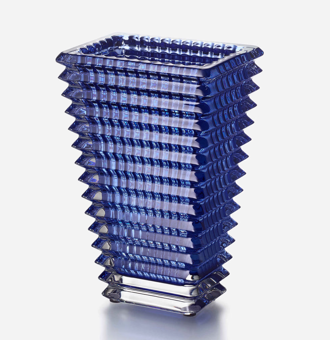 The Eye Vase Rectangular Small - Blue by Baccarat features a tall, geometric blue glass design with a square base that widens at the top and stepped ridges for a modern, architectural look against a plain white background.