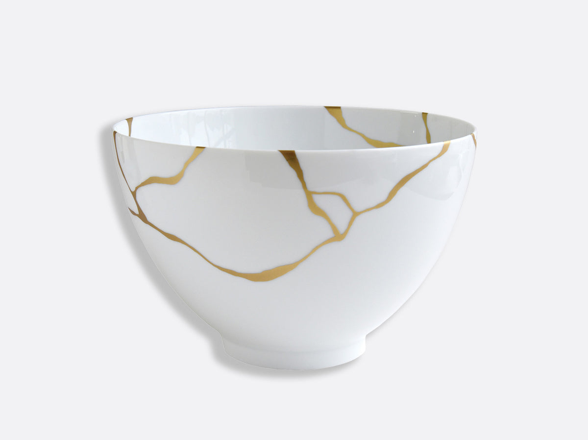 The Bernardaud Kintsugi Dinnerware features a white ceramic bowl with gold cracks, inspired by the Japanese art of Kintsugi, symbolizing beauty in imperfection and refined craftsmanship against a plain light background.