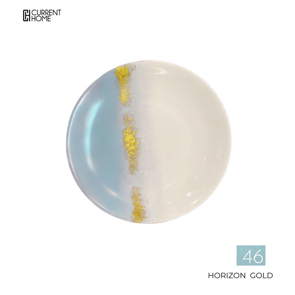 A Marie Daâge Horizon Gold Dinnerware round plate features blue left, white right, and a vertical gold accent. Current Home logo is top left; "Horizon Gold 46" appears bottom right.