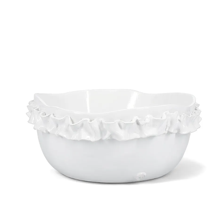 The Montes Doggett Ceramic Serveware - Bowl 682 is a white ceramic bowl featuring a ruffled, wavy rim that adds a decorative and elegant touch. Expertly crafted as artisan pottery, this high fired bowl boasts a smooth glossy finish and sits beautifully on any surface.
