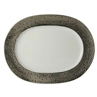 The Ecume Platinum Dinnerware by Bernardaud features an oval white plate with a textured, dark metallic border adorned with small, irregular dots—ideal for a contemporary table setting or enhancing your Bernardaud collection.