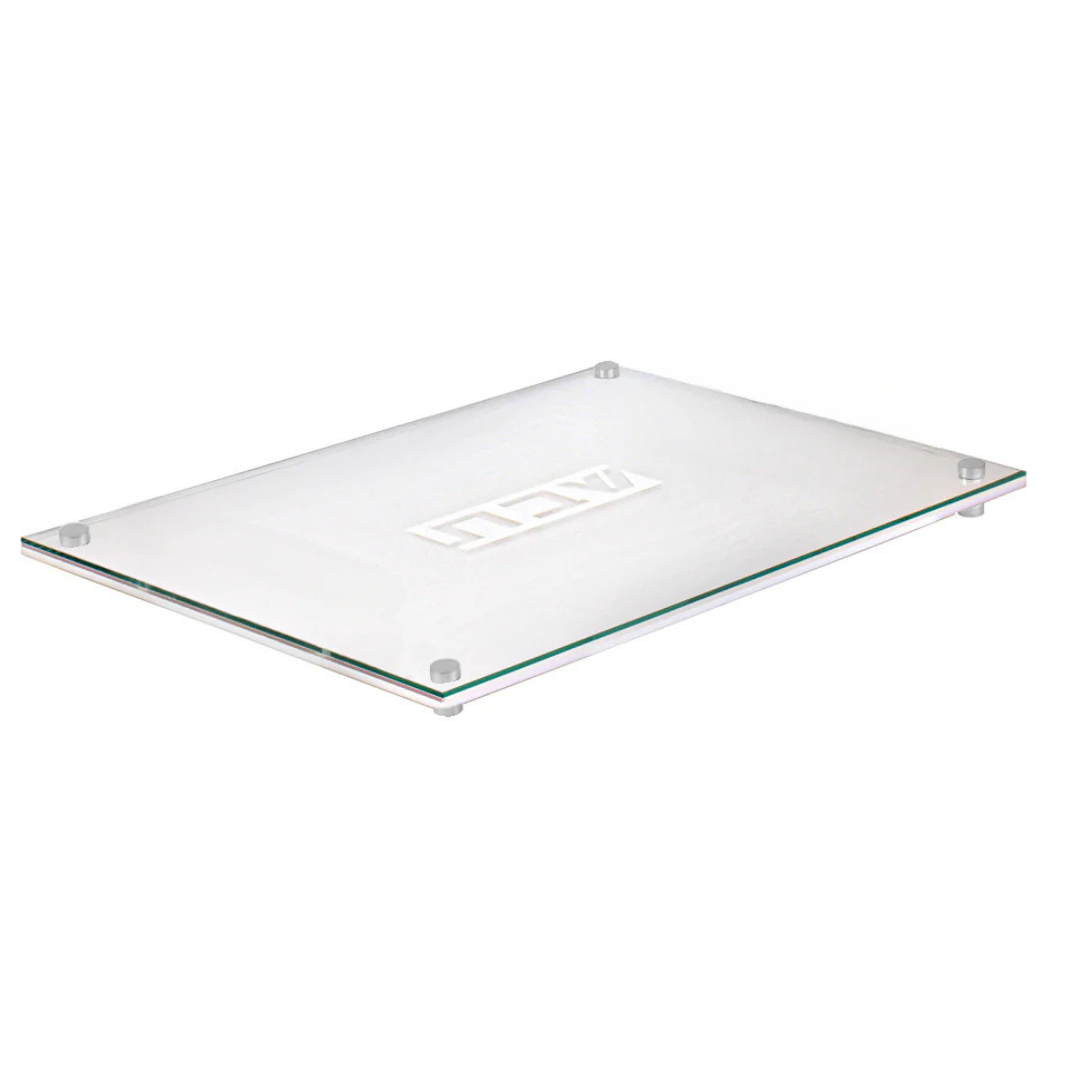 The BT-Shalom Lucite Corrugated Challah Board features a rectangular glass design with four non-slip feet and a central logo, making it ideal for modern tablescapes. Shown on a white background.
