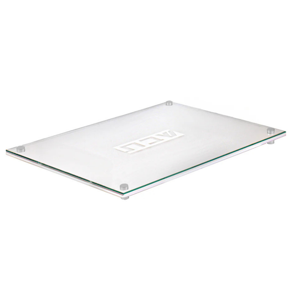The BT-Shalom Lucite Corrugated Challah Board features a rectangular glass design with four non-slip feet and a central logo, making it ideal for modern tablescapes. Shown on a white background.