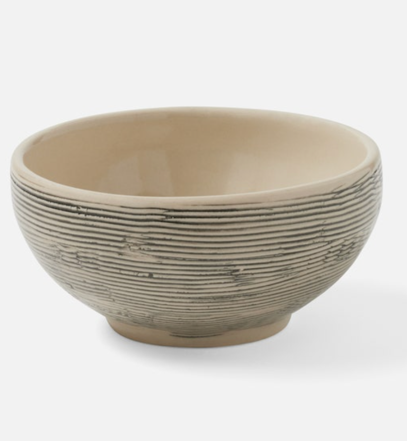 The Blue Pheasant Nolan Dinnerware Black Cream is a round ceramic bowl from an artisanal collection, featuring a smooth beige interior and a ridged, darker exterior, shown on a plain white background.