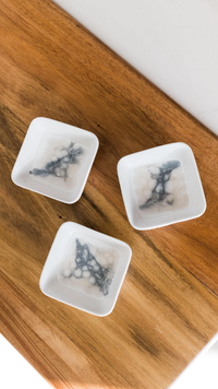 Three Lynn & Liana Serveware Painted Dip Bowls - Marble sit on a wooden surface, each holding a pale translucent dessert with dark marbled streaks and small round balls inside.