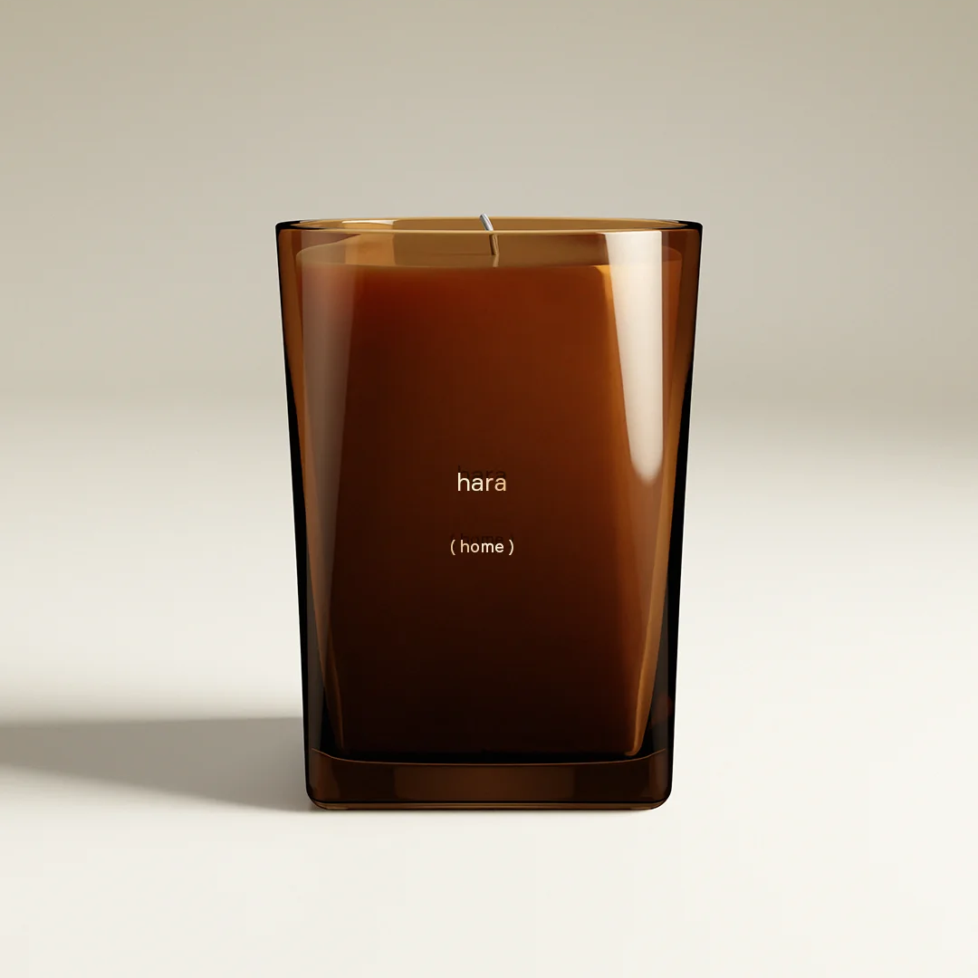 Hara (Home) candle in a square, translucent amber glass jar with a botanical fragrance.