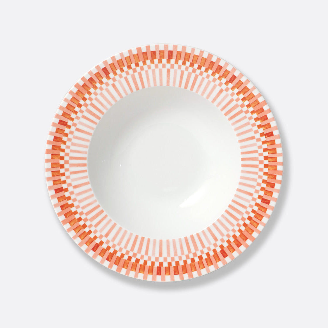 A white Terra Rosa Dinnerware bowl by Bernardaud, featuring an orange and pink geometric rim of rectangles and lines, is shown from above on a light gray background. Made in Limoges, France.