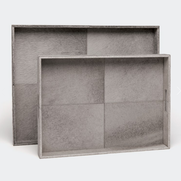 The Made Goods Renard Rectangle Hide Grey Trays feature two silver-gray leather trays with subtle texture and panel details; the smaller tray is set in front of the larger one, both upright against a light background.